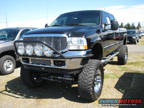 Black lifted pickup truck with chrome grille, bull bar, and four auxiliary lights