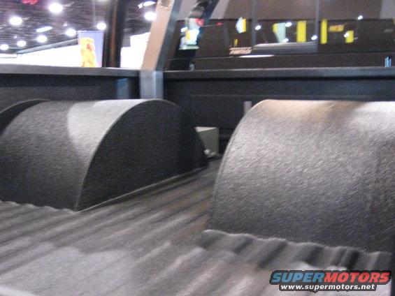 Truck bed interior with two black textured wheel wells and ribbed floor