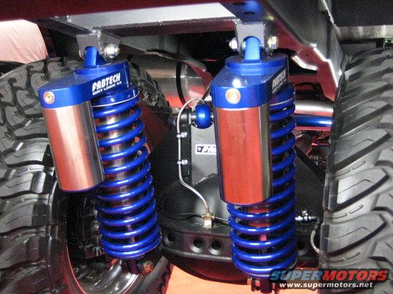 Rear suspension with blue Fabtech coilover shocks and large off-road tires