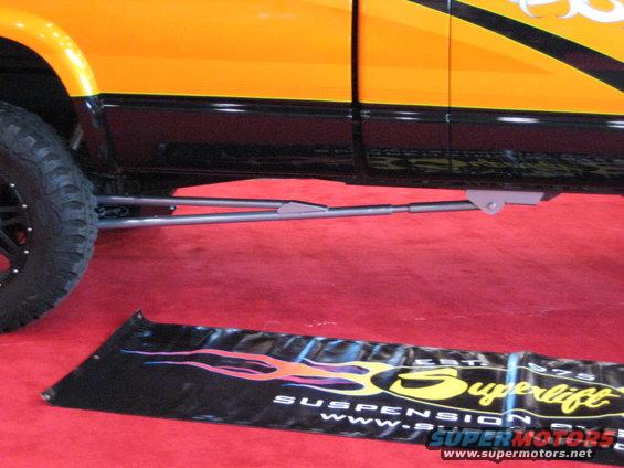 side view of a lifted pickup truck with custom suspension components and orange and black paint
