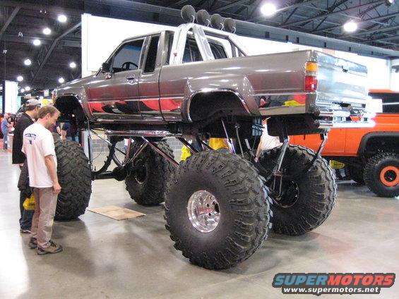 Gray lifted pickup truck with large tires and chrome trim, viewed from the front-right