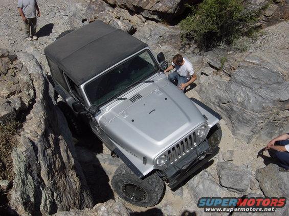 Silver 2004 Jeep Wrangler TJ Rubicon navigating a rocky trail, with people observing