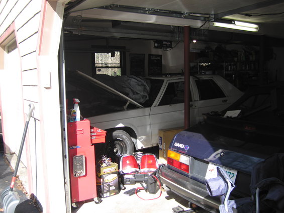 White 1991 Ford Crown Victoria LTD with hood open, next to a blue Saab hatchback in a garage