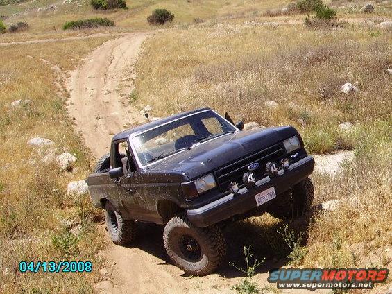 Black 1990 Ford Bronco on a dirt trail, front 3/4 view