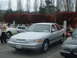 1987 Ford Crown Victoria LTD - A silver sedan is parked in a lot with other vehicles and trees in the background.