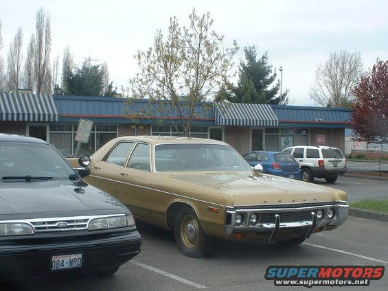 Gold 1973 Ford sedan parked in a lot, front quarter view. Chrome bumper and grille visible