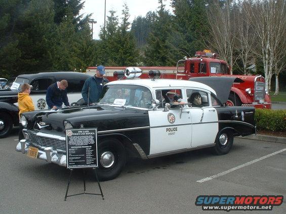 Black and white 1956 police car replica with "POLICE" text on the door