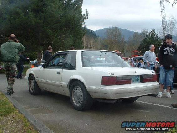 White coupe with a license plate reading 00542, seen from the rear