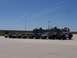 1990 Ford Bronco - A row of SUVs and trucks are parked in front of hovercraft under a clear blue sky.