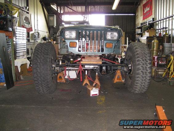 Jeep Wrangler on jack stands in a garage, front end visible, large tires