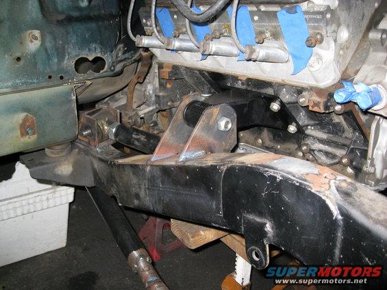 Custom engine mount bracket welded to frame rail, with engine block and transmission visible