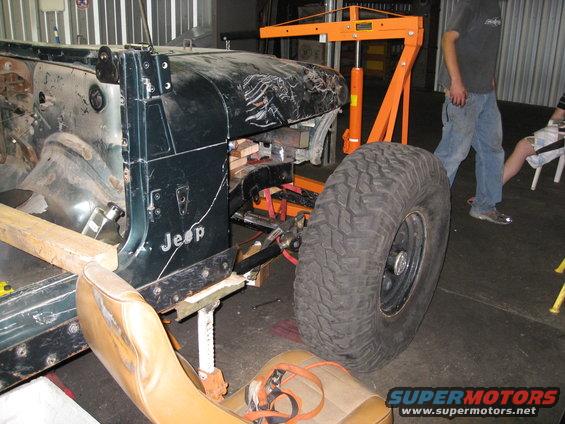 Jeep YJ body on jack stands, front fender removed, large tire attached