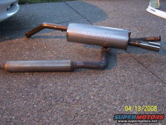 Borla exhaust system laid out on asphalt. A car fender is visible on the left