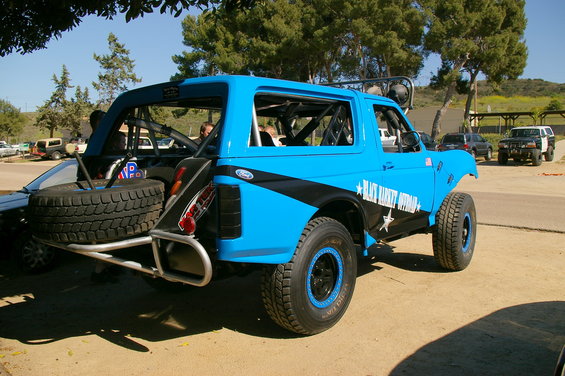Blue 1986 Ford Bronco off-road with spare tire carrier and "Black Market Offroad" decal