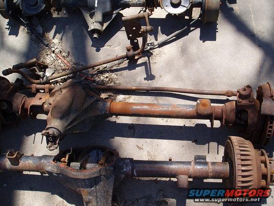 two rusty vehicle axles laid out on concrete