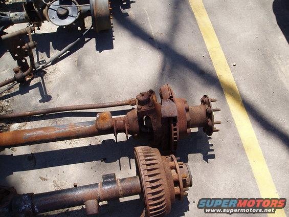 Rusty front and rear axles with brake drums and rotors on concrete
