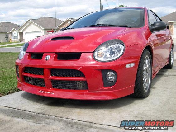 Red Dodge Neon SRT-4 parked on a driveway, front quarter view. Hood scoop and custom front bumper visible