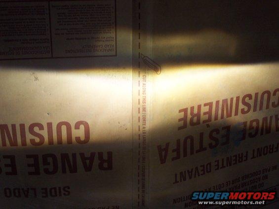 Headlight beam shining on a cardboard box with French text about a range and oven