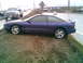 1996 Ford Probe - A purple 1996 Ford Probe is parked on the side of a wet highway, with a white pickup truck in the background.
