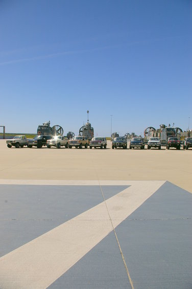 Several SUVs and trucks parked in a line on a paved surface under a clear blue sky