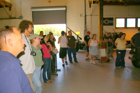 People gathered inside a large building, looking towards an open garage door