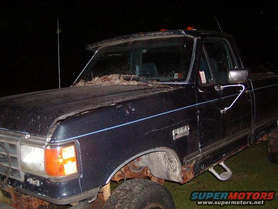 Dark blue pickup truck, 3/4 front view. Rusty body and fender