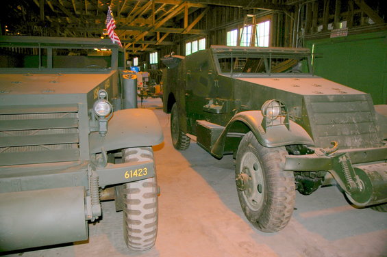 Two olive drab military half-track vehicles parked indoors. One has '61423' on its fender