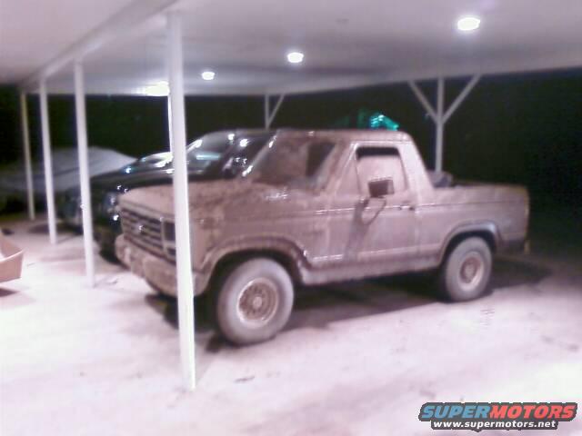 Mud-caked pickup truck parked under a carport next to another vehicle