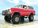 1978 Ford Bronco - This lifted 1978 Ford Bronco, painted red and white, is parked on a beach with shallow water around its tires.