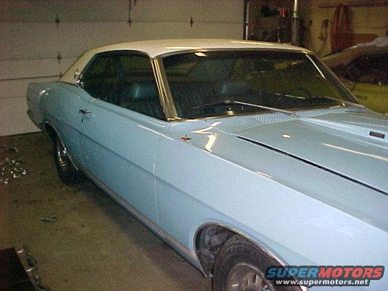 Light blue 1969 Ford Torino coupe with a white roof, seen from the front 3/4 angle in a garage