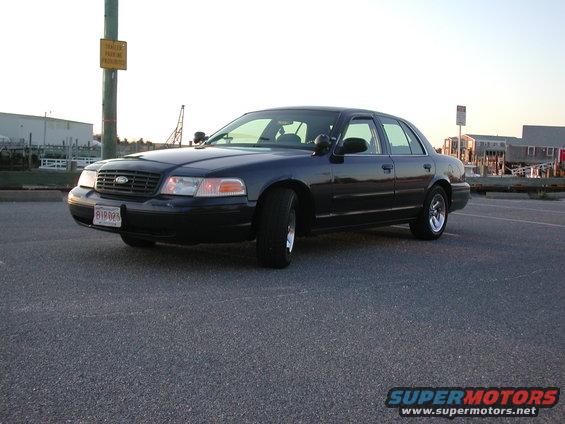 Dark blue Ford Crown Victoria parked near a waterfront. License plate reads B18-025