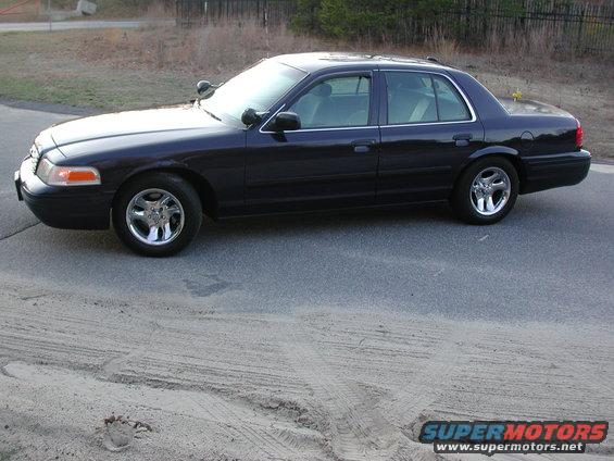 Dark blue sedan parked on asphalt, side view, chrome wheels, visible light-colored interior