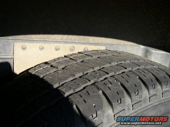 Tire tread and riveted metal panel in wheel well