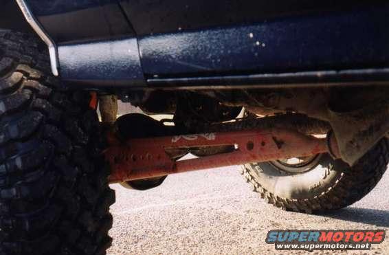 Dark blue Ford Bronco underside with large off-road tires and red suspension components