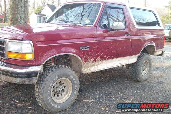 Maroon 1993 Ford Bronco with mud splatters, lifted suspension, and off-road tires