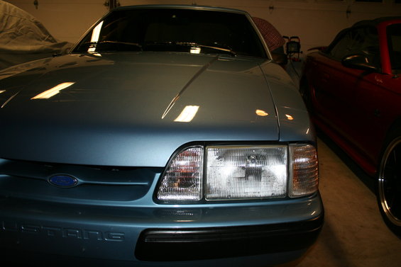 Front view of a blue 1990 Ford Mustang parked next to a red car
