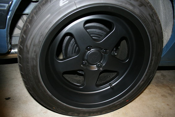 Black five-spoke aftermarket wheel on a car tire, close-up