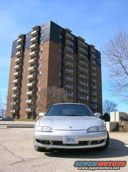 Silver coupe parked in front of a brick apartment building. License plate reads ONPOC