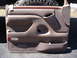 1996 Ford Bronco - This is a tan door panel from a 1996 Ford Bronco, wood trim and a storage pocket.