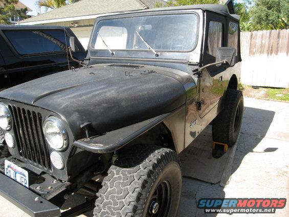 Black Jeep CJ7 with soft top, parked next to a black SUV