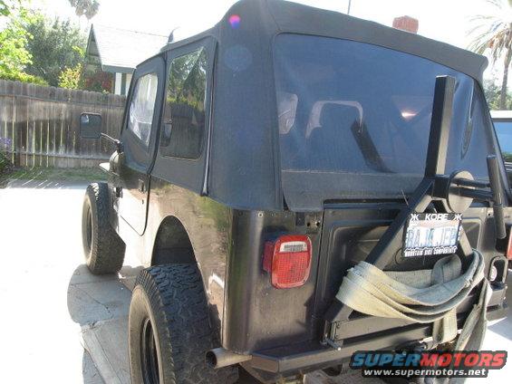 Black Jeep CJ with soft top, spare tire carrier, and license plate