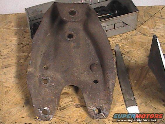 rusted metal suspension part with holes, next to a saw blade