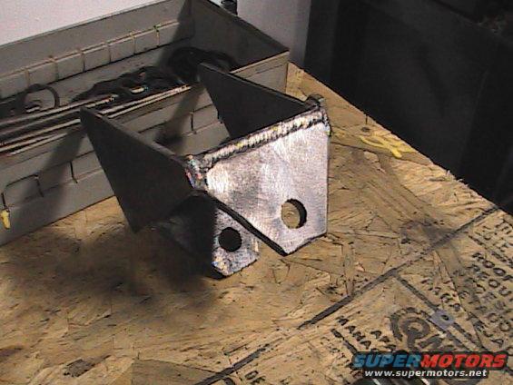 welded metal bracket on a wooden surface with a toolbox in the background