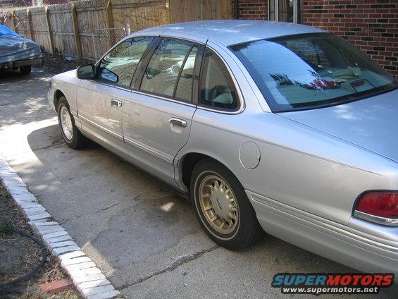 1996 Ford Crown Victoria side view, parked on driveway. Another car is partially visible to the left
