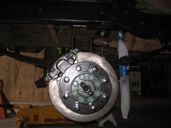 Disc brake assembly with green lug nuts and black caliper