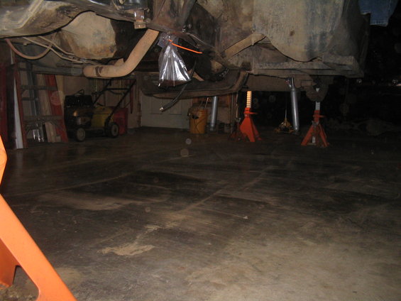 Undercarriage of vehicle on jack stands, showing suspension and exhaust components