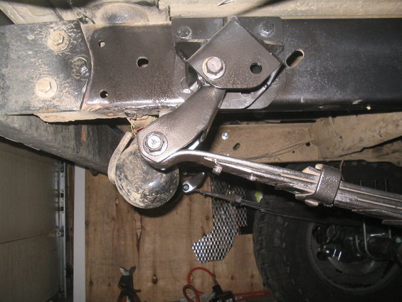 Underside view of a vehicle's frame with suspension parts, including a leaf spring and shock absorber