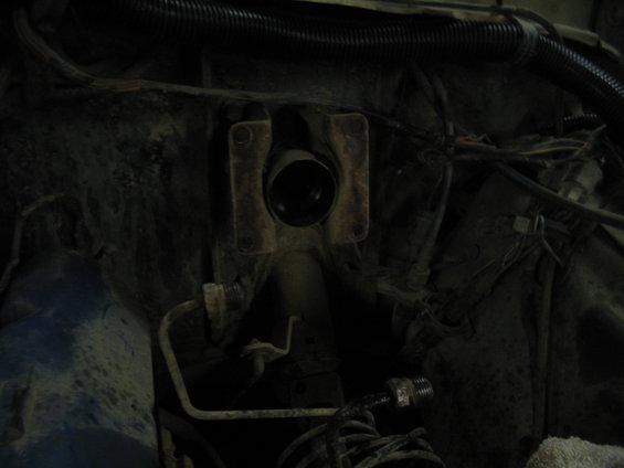 Engine bay with hoses and wiring, showing a metal bracket with a circular opening