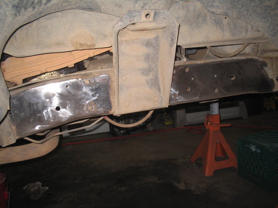 Vehicle frame section with patches welded on, supported by an orange jack stand