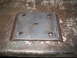 1979 Ford Bronco - A fabricated metal plate with multiple holes and welded edges rests on a textured surface.